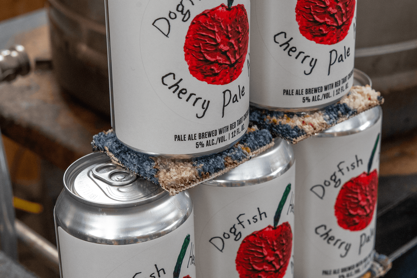Dogfish Cherry Pale Ale cans stacked on a wooden surface