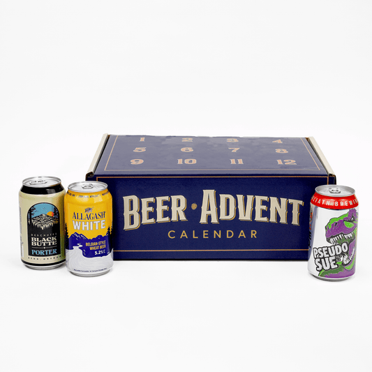 A beer advent calendar set featuring a dark blue box labeled 'BEER ADVENT CALENDAR' with four assorted craft beer cans placed in front on a clean white background.