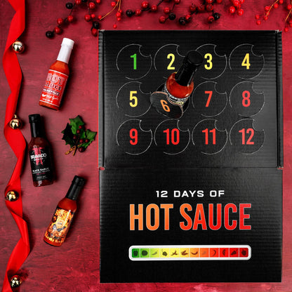 A 12-day hot sauce advent calendar box on a red holiday-themed background, surrounded by individual hot sauce bottles, red berries, and a red ribbon.
