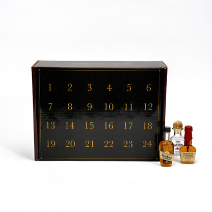 A black 24-day whiskey advent calendar box with gold numbers on the front, shown with several small branded whiskey bottles on a white studio background.