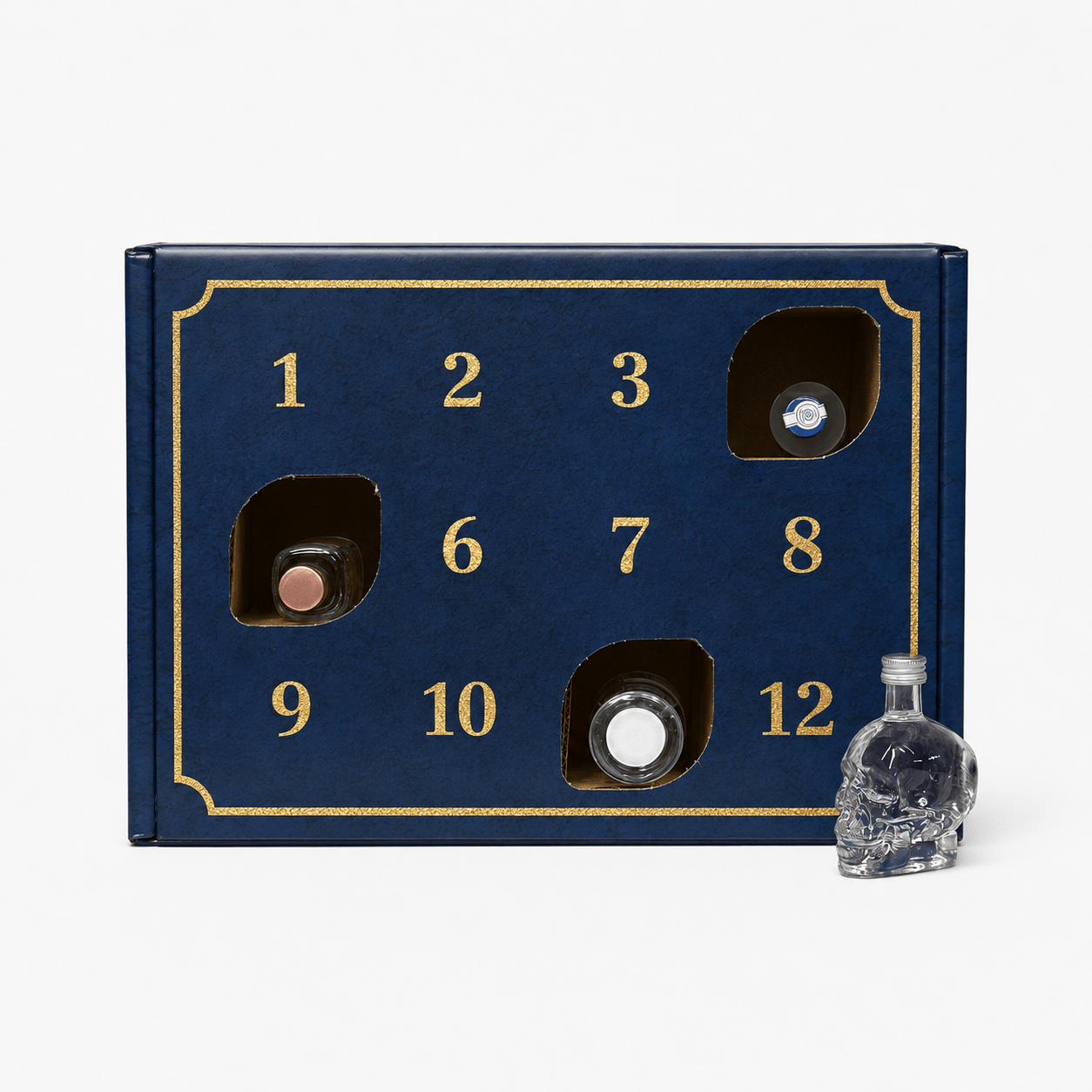 A dark blue advent calendar box with gold trim and numbered compartments, shown open with several small bottles inside, plus a small clear skull-shaped bottle on a white background.
