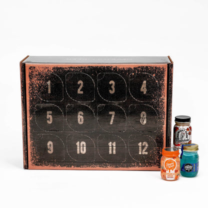 A 12-day moonshine advent calendar box with numbered compartments on the front, shown on a white background with three small jars of colorful spices or candies beside it.