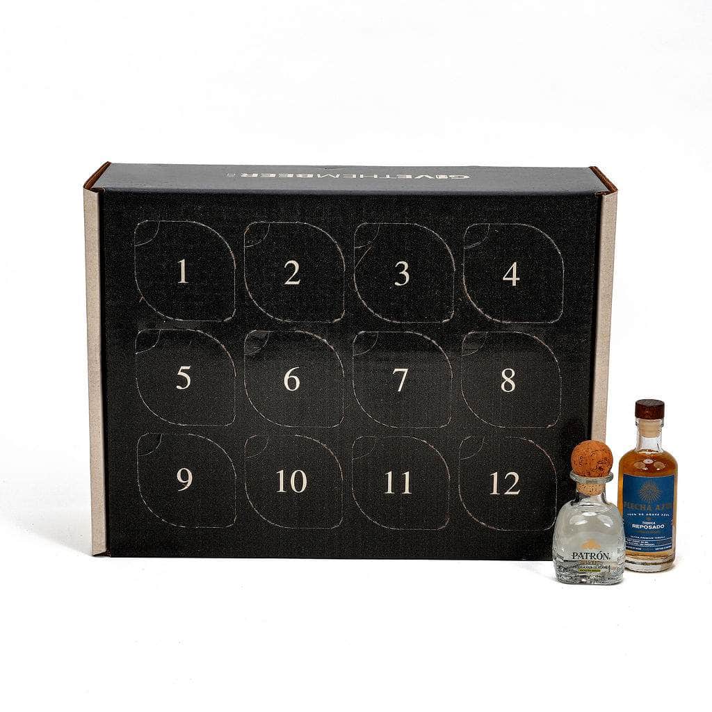 A black 12-day advent box for tequila, shown with two miniature bottles of patron and flecha azul in front on a white background. The box features 12 numbered compartments on the front.