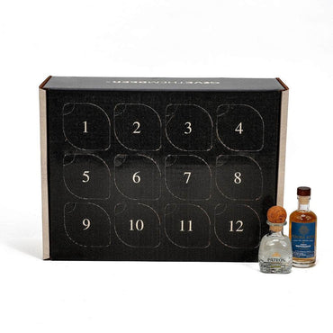A black 12-day advent box for tequila, shown with two miniature bottles of patron and flecha azul in front on a white background. The box features 12 numbered compartments on the front.