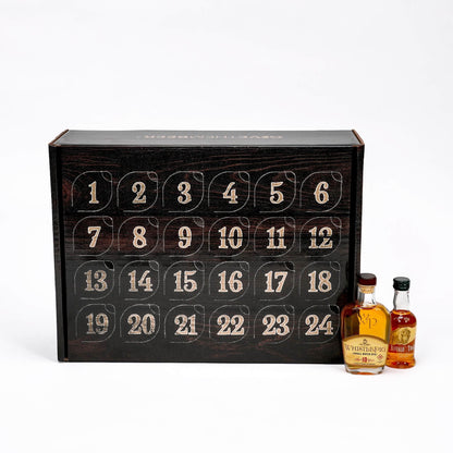 A 24-door whisky advent calendar box with numbered compartments, shown open with two miniature bottles of whisky in front on a white background.